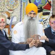 Pupils Emily Kay and Jordan Astley, both aged 11, meet Roop Singh, holding the One God symbol. The children had their faces painted Hindu style