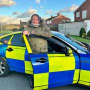 Graham Cole OBE who is known for playing PC Tony Stamp in The Bill, standing with the police car