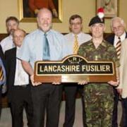 NAMEPLATE: Colonel Brian Gorski, front, in uniform, receives the Lancashire Fusiliers nameplate, from the Metrolink tram which bears the regimental name, from Andy Morris of Stagecoach Metrolink.
