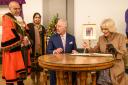 Their Majesties sign a book. Picture: Paul Heyes