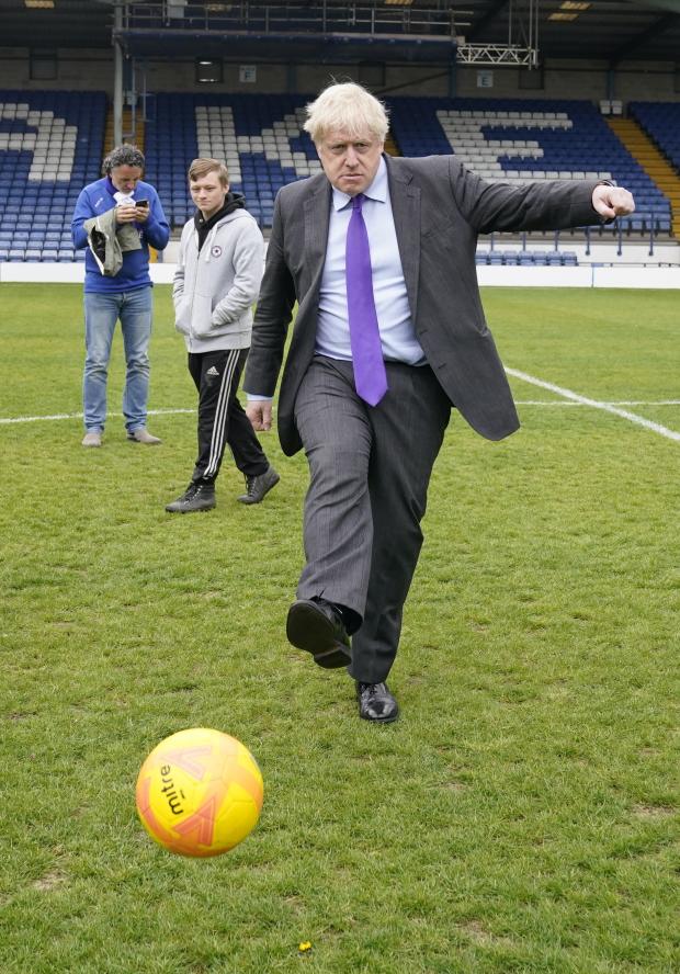 Bury Times: Boris Johnson kicks a football at Gigg Lane. Photo: PA 