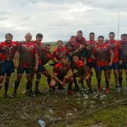 A muddied Bury Broncos side celebrate going top of NWML Division Two following a 17-0 victory at Rochdale Mayfield A