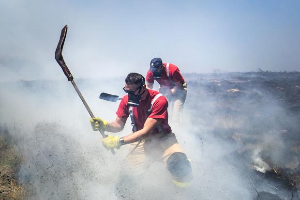 Firefighters continue to work on Winter Hill near Bolton. PRESS ASSOCIATION Photo. Picture date: Tuesday July 3, 2018. Fire chiefs declared a major incident on Saturday after two large-scale blazes either side of Winter Hill near Bolton merged because of 